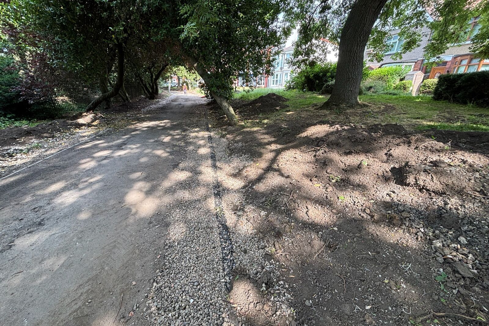 Tree-lined park path with the flush drainage line dressed in gravel along its edge